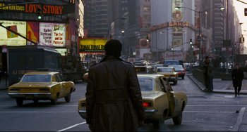 Movie still from “Shaft” (1971), directed by Gordon Parks – A man in a trench coat is crossing a busy street; Wide shot, Over the shoulder angle