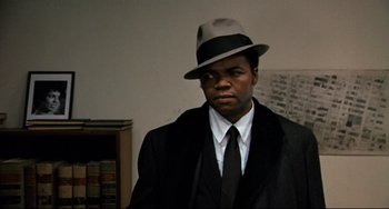 Movie still from “Shaft” (1971), directed by Gordon Parks – A man wearing a hat and a suit; Close Up shot, Over the shoulder angle
