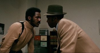 Movie still from “Shaft” (1971), directed by Gordon Parks – Two men are talking in front of each other in a room; Medium shot, Over the shoulder angle