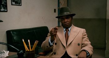 Movie still from “Shaft” (1971), directed by Gordon Parks – A man wearing a hat and a suit and tie; Medium shot, Over the shoulder angle