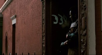 Movie still from “Shaft” (1971), directed by Gordon Parks – A man standing in front of a brick building; Medium shot, Over the shoulder angle