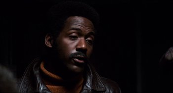 Movie still from “Shaft” (1971), directed by Gordon Parks – A black man with a leather jacket and a beard; Close Up shot, Low angle