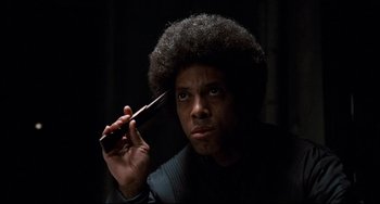 Movie still from “Shaft” (1971), directed by Gordon Parks – A man holding a cell phone up to his face; Close Up shot, Low angle