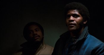 Movie still from “Shaft” (1971), directed by Gordon Parks – Two men standing next to each other in a dark room; Close Up shot, Low angle