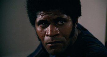 Movie still from “Shaft” (1971), directed by Gordon Parks – A man's face in a dark room; Close Up shot, Low angle