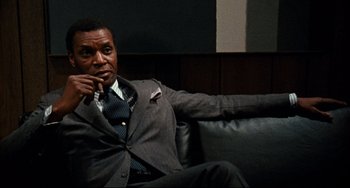 Movie still from “Shaft” (1971), directed by Gordon Parks – A man sitting on a couch smoking a cigarette; Close Up shot, Low angle