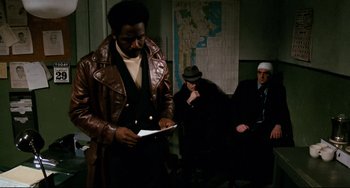 Movie still from “Shaft” (1971), directed by Gordon Parks – A man wearing a brown leather jacket and a hat; Medium shot, Over the shoulder angle