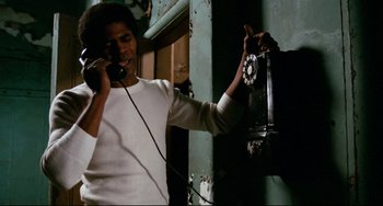 Movie still from “Shaft” (1971), directed by Gordon Parks – A man holding up a phone to his ear; Medium shot, Low angle