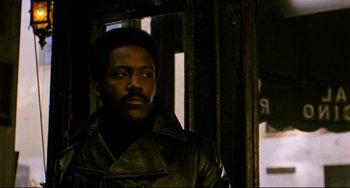 Movie still from “Shaft” (1971), directed by Gordon Parks – A man wearing a leather jacket standing next to a window; Close Up shot, Low angle
