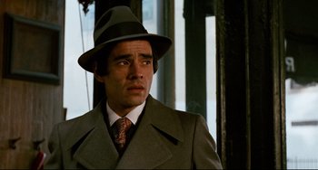 Movie still from “Shaft” (1971), directed by Gordon Parks – A man wearing a suit and a hat looking to his left; Close Up shot, Over the shoulder angle