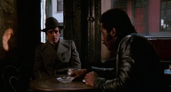 Movie still from “Shaft” (1971), directed by Gordon Parks – Two men sitting at a table in front of each other; Medium shot, Over the shoulder angle