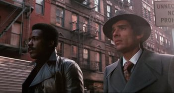 Movie still from “Shaft” (1971), directed by Gordon Parks – A man in a suit and a hat standing next to another man in a suit; Medium shot, Low angle
