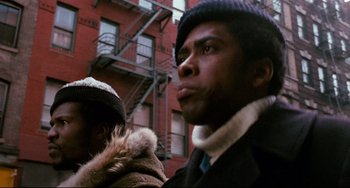Movie still from “Shaft” (1971), directed by Gordon Parks – Two men standing next to each other in front of a building; Close Up shot, Low angle