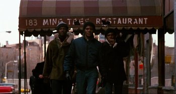 Movie still from “Shaft” (1971), directed by Gordon Parks – A group of men standing next to each other on the sidewalk; Wide shot, Low angle