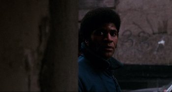 Movie still from “Shaft” (1971), directed by Gordon Parks – A man in a blue jacket standing next to a tree; Close Up shot, Low angle