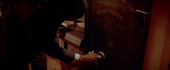 Movie still from “Shaft's Big Score!” (1972), directed by Gordon Parks – A man in a suit and tie putting money in a safe; Extreme Close Up shot, High angle