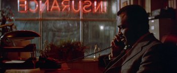 Movie still from “Shaft's Big Score!” (1972), directed by Gordon Parks – A man sitting at a table talking on a phone; Close Up shot, Low angle