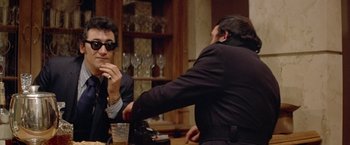 Movie still from “Shaft's Big Score!” (1972), directed by Gordon Parks – Two men sitting at a table in front of each other; Medium shot, Over the shoulder angle