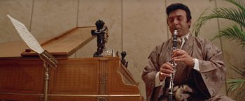 Movie still from “Shaft's Big Score!” (1972), directed by Gordon Parks – A man playing the clarinet in front of a piano; Close Up shot, Low angle