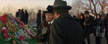 Movie still from “Shaft's Big Score!” (1972), directed by Gordon Parks – Two men in hats and coats are standing in front of a grave; Medium shot, Over the shoulder angle