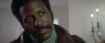 Movie still from “Shaft's Big Score!” (1972), directed by Gordon Parks – A person wearing a brown jacket; Close Up shot, Low angle