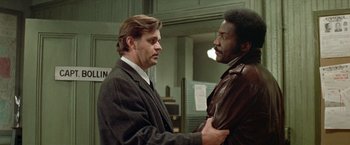 Movie still from “Shaft's Big Score!” (1972), directed by Gordon Parks – Two men in suits are talking to each other; Medium shot, Low angle