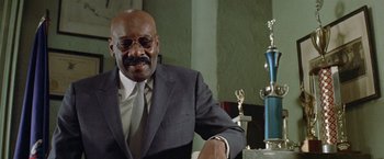 Movie still from “Shaft's Big Score!” (1972), directed by Gordon Parks – An older man sitting in front of a trophy; Close Up shot, Low angle