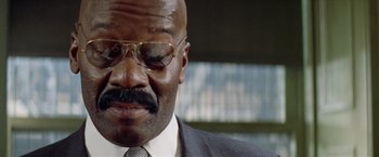 Movie still from “Shaft's Big Score!” (1972), directed by Gordon Parks – A man with a mustache wearing glasses and a suit; Close Up shot, Low angle