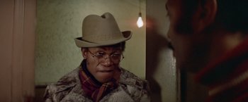 Movie still from “Shaft's Big Score!” (1972), directed by Gordon Parks – A man wearing a hat and glasses looking at a mirror; Close Up shot, Low angle