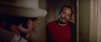 Movie still from “Shaft's Big Score!” (1972), directed by Gordon Parks – A man in a red sweater looking at himself in the mirror; Close Up shot, Over the shoulder angle