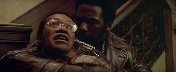Movie still from “Shaft's Big Score!” (1972), directed by Gordon Parks – A man and a woman holding a gun in a room; Close Up shot, Low angle