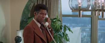 Movie still from “Shaft's Big Score!” (1972), directed by Gordon Parks – An older man in a brown suit talking on a phone; Close Up shot, High angle