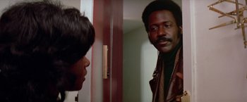 Movie still from “Shaft's Big Score!” (1972), directed by Gordon Parks – A man standing next to a woman in a doorway; Close Up shot, Low angle