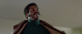Movie still from “Shaft's Big Score!” (1972), directed by Gordon Parks – A black man with a beard and a green sweater; Close Up shot, Low angle