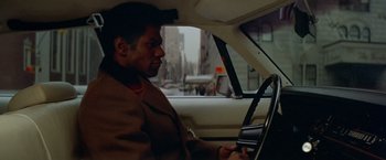 Movie still from “Shaft's Big Score!” (1972), directed by Gordon Parks – A man sitting in the driver's seat of a car; Medium shot, Over the shoulder angle