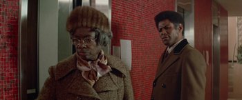 Movie still from “Shaft's Big Score!” (1972), directed by Gordon Parks – A man and a woman standing next to each other in front of a brick wall; Medium shot, Low angle