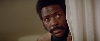 Movie still from “Shaft's Big Score!” (1972), directed by Gordon Parks – A person looking at the camera; Close Up shot, Low angle