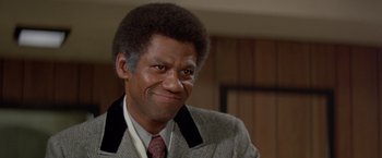 Movie still from “Shaft's Big Score!” (1972), directed by Gordon Parks – A person wearing a suit and tie; Close Up shot, Low angle