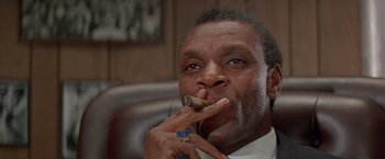 Movie still from “Shaft's Big Score!” (1972), directed by Gordon Parks – A person holding a cigar in his mouth; Close Up shot, Low angle