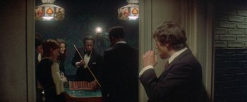Movie still from “Shaft's Big Score!” (1972), directed by Gordon Parks – A man in a suit and tie standing next to a pool table; Medium shot, Over the shoulder angle