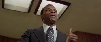Movie still from “Shaft's Big Score!” (1972), directed by Gordon Parks – A man in a suit and tie holding a baseball bat; Close Up shot, Low angle