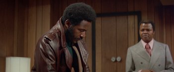 Movie still from “Shaft's Big Score!” (1972), directed by Gordon Parks – A man in a leather jacket and a tie; Close Up shot, Low angle