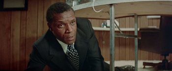 Movie still from “Shaft's Big Score!” (1972), directed by Gordon Parks – A man in a black suit and a black tie; Close Up shot, Low angle