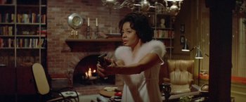 Movie still from “Shaft's Big Score!” (1972), directed by Gordon Parks – A woman holding a remote control in a living room; Medium shot, Over the shoulder angle