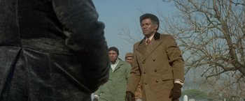 Movie still from “Shaft's Big Score!” (1972), directed by Gordon Parks – A group of men standing next to each other on a field; Medium shot, Low angle
