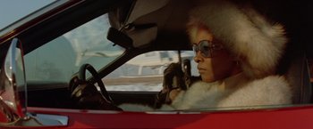 Movie still from “Shaft's Big Score!” (1972), directed by Gordon Parks – A woman sitting in the driver's seat of a red car; Close Up shot, Low angle