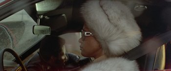Movie still from “Shaft's Big Score!” (1972), directed by Gordon Parks – A woman wearing a white fur hat in the backseat of a car; Close Up shot, Low angle