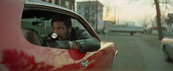 Movie still from “Shaft's Big Score!” (1972), directed by Gordon Parks – A man sitting in the driver's seat of a red sports car; Close Up shot, Low angle