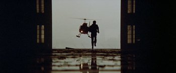 Movie still from “Shaft's Big Score!” (1972), directed by Gordon Parks – A man standing in front of a helicopter in the rain; Wide shot, Low angle