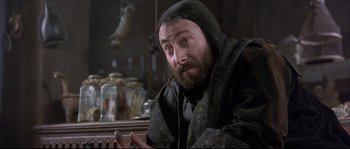 Movie still from “Shakespeare in Love” (1998), directed by John Madden – A man with a beard is sitting at a table; Close Up shot, Low angle